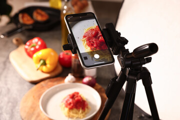 Shooting tasty pasta with smartphone in studio, selective focus. Professional food photography