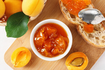 Tasty apricot jam and fresh fruits on white table, flat lay