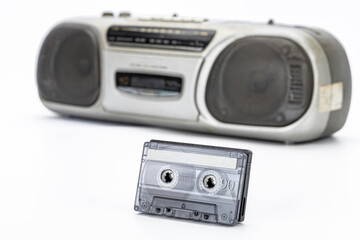Vintage cassette tape, transparent plastic, and retro portable audio player evoke nostalgia, music memories, and classic analog sound in white studio background
