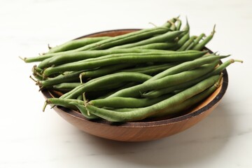 Fresh pea pods in bowl on white marble table, closeup