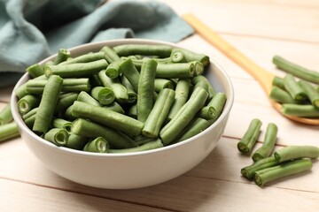 Pieces of fresh pea pods in bowl on light wooden table, closeup