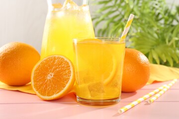 Refreshing soda water with orange slice in glass, jug and fresh fruits on pink wooden table, closeup