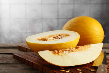 Cut and whole ripe melons on wooden table, closeup