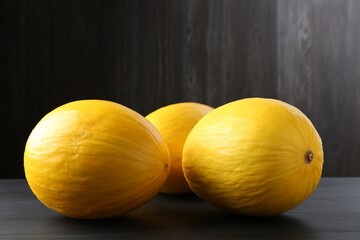Whole ripe melons on black wooden table