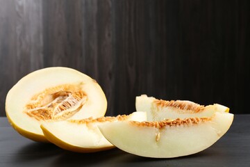 Cut ripe melon on black wooden table, closeup