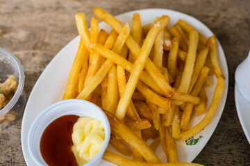 A pile of crunchy french fries served with ketchup and mayonnaise
