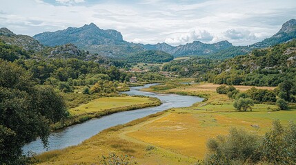 Fototapeta premium Serene river winding through a valley flanked by mountains and lush greenery