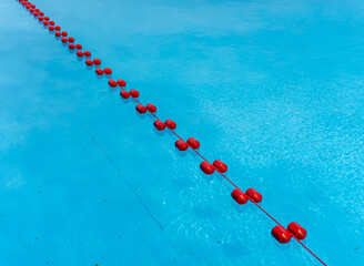 Clear blue swimming pool water with a red buoy line separating the swimming lane, top view highlighting strong color contrast and water transparency.