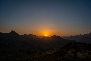Obraz premium yellow and orange sunrise with layers of the mountains in Damüls Bregenzer Wald in Vorarlberg Austria seen from Portlahorn with negative space for text