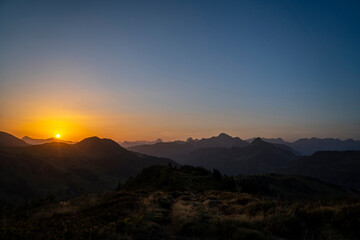 yellow and orange sunrise with layers of the mountains in Damüls Bregenzer Wald in Vorarlberg Austria seen from Portlahorn with negative space for text
