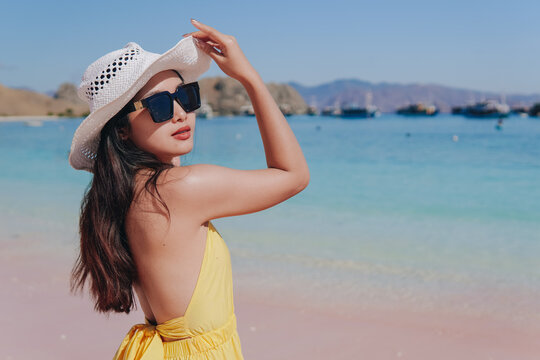 Back view of a carefree young Asian standing and enjoying the pink beach scenery in Labuan Bajo.