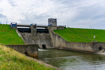 Concrete Mietk&oacute;w dam in Lower Silesia with visible water spillway, surrounded by green flood embankments, serving as flood protection and water level regulation infrastructure.