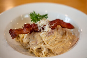 Spaghetti Carbonara with ham and bacon served on a white plate. Soft Focus.