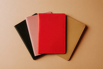 Stack of four colorful leather bound notebooks on a beige background in an overhead shot flat lay style
