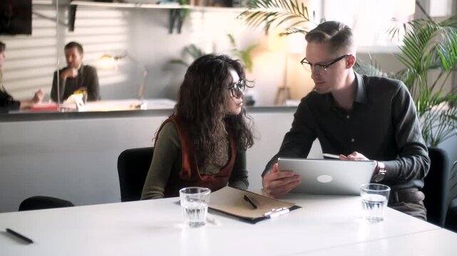 Businessman And Woman Clients Talking Strategy With Tablet At Office Desk. In Creative Office Productive Coworkers Sitting At The Table For Company Meeting. Teamwork And Social Concepts