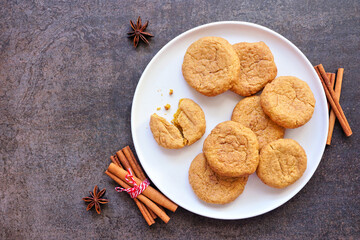 Plate of autumn pumpkin spice snickerdoodles. Top down view table scene with a dark stone background.
