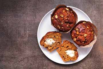 Cream cheese filled autumn pumpkin muffins. Above view on a rustic dark background.