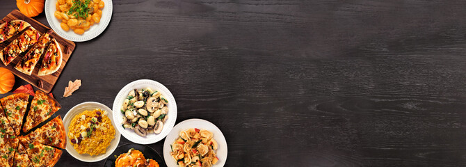 Delicious autumn meal corner border. Top down view on a black wood banner background. Pumpkin and apple theme risotto, pasta, gnocchi, flat bread and pizza.