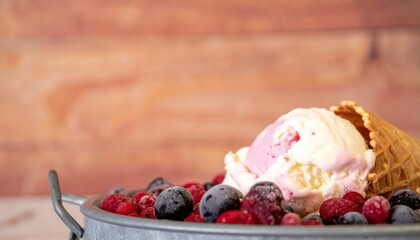 vanilla and pink ice cream in a pial with frozen berries and waffle cone