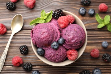 Delicious sorbet with fresh berries and mint in bowl on wooden table, flat lay