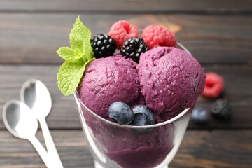 Delicious sorbet with fresh berries and mint in glass dessert bowl on wooden table, closeup