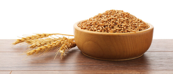 Wheat grains in bowl and spikes on wooden table against white background