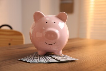 Piggybank and dollar banknotes on wooden table