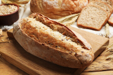 Different types of bread, grains and wheat spikes on wooden table, closeup