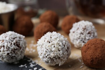 Delicious homemade candies with cocoa powder and coconut flakes on wooden table, closeup