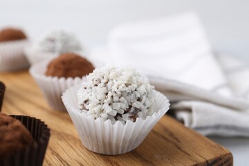 Delicious homemade candies with coconut flakes and cocoa powder on table, closeup