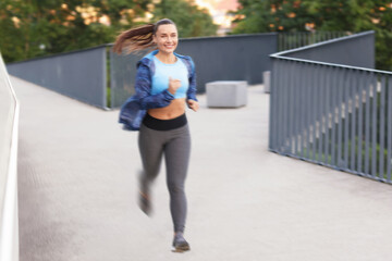 Woman in sportswear running outdoors, motion blur effect