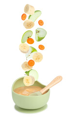 Baby food. Slices of apple, banana and carrot falling into bowl of puree on white background