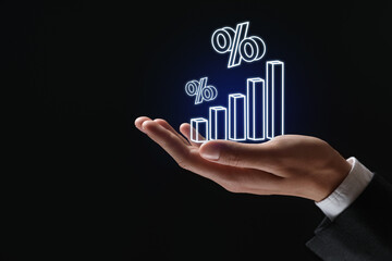 Businessman holding virtual graph and percent signs against black background, closeup