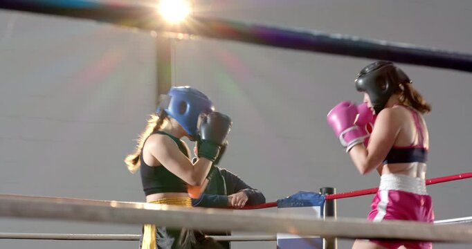 Boxers meeting in boxing ring exchanging gloved jabs while coach stepping over ropes to coach