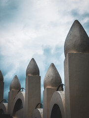 A dramatic low-angle shot of a mosque's dome-like structures reaching towards a moody, cloudy sky, highlighting the unique architecture.