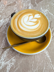 Latte art in coffee on yellow plate