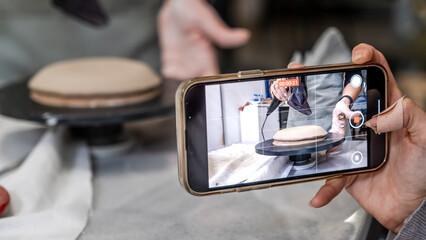 In an art studio a beautiful middle-aged woman artist is shaping clay at a table, while a young...