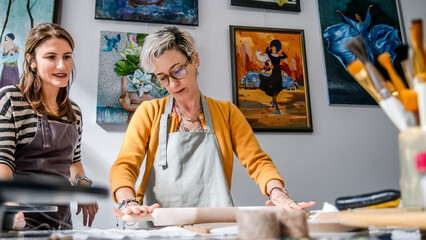 In an art studio with an environment adorned with artistic paintings in the background, two...