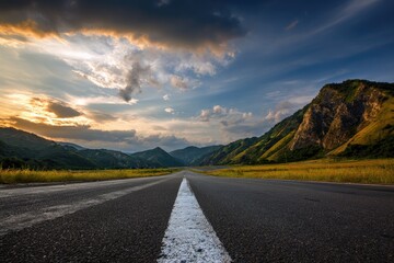 Asphalt road stretches into a mountainous landscape at sunset