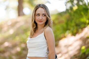 Fototapeta premium Woman posing outdoors in a forested area on a sunny day with greenery surrounding her