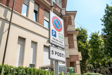 Road sign for reserved parking spaces for electric vehicles while charging in an urban context. Ideal for illustrating concepts of sustainability, technological innovation, and green infrastructure.