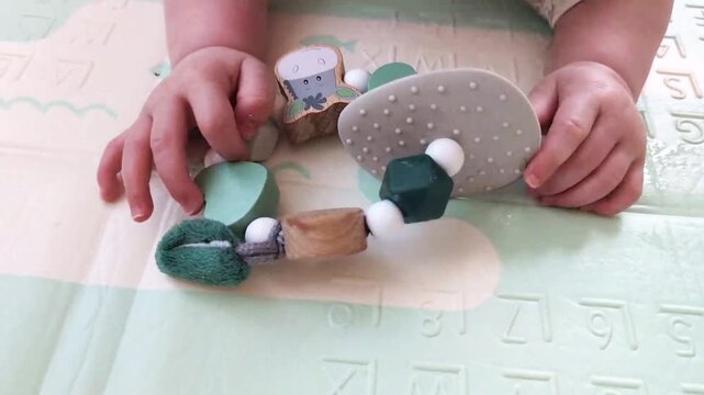 baby hands holding sensory teething toy on alphabet playmat early development and tactile exploration concept