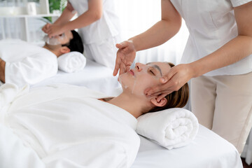 Obraz premium Serene modern daylight ambiance of spa salon, couple customer indulges in rejuvenating with facial skincare mask. Facial skin treatment and beauty cosmetology procedure for face. Quiescent