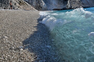 Fale bijące o brzeg, drobne okrągłe kamyczki.  Plaża Myrtos na greckiej wyspie Kefalonia, uważana za jedną z dziesięciu najpiękniejszych plaż świata