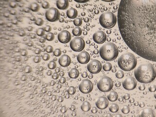 Close up of transparent bubbles floating on liquid surface with abstract pattern