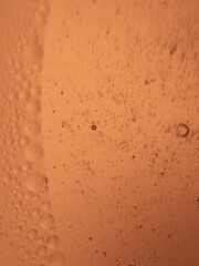 Close-up of bubbles suspended in orange liquid with abstract pattern