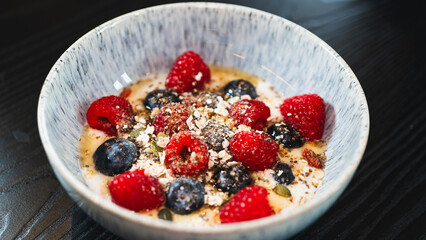 Nutritious yogurt parfait with fresh raspberries, blueberries, oats, chia seeds and honey drizzle. Perfect for healthy food blogs and breakfast photography.