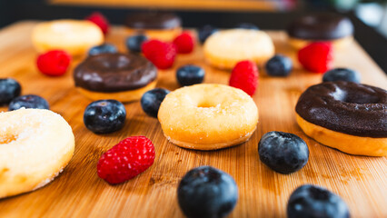 Beautifully styled donut platter featuring chocolate glazed, sugar dusted, blueberry and raspberry donuts. Perfect for bakery marketing, food blogs and party styling