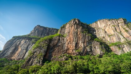 Fototapeta premium majestic rugged cliff face with vibrant green foliage under a clear blue sky capturing the serene beauty of a natural landscape