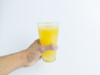 Hand holding a full glass of fresh orange juice on a white background. Healthy vitamin C drink, refreshing breakfast beverage, and nutritious fruit juice isolated for food and drink concepts.
